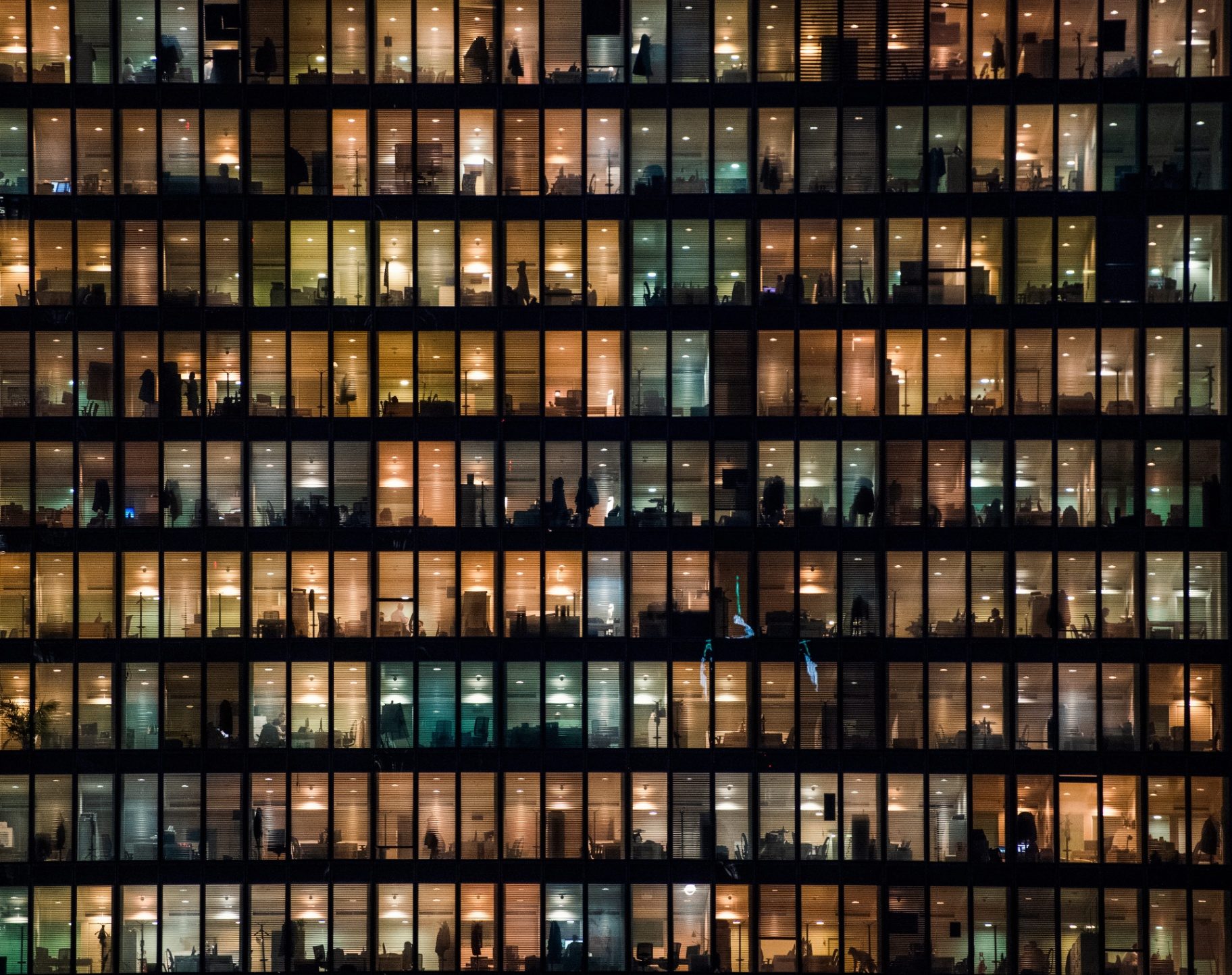 Illuminated windows of a UK office tower at night, representing office insurance for commercial premises